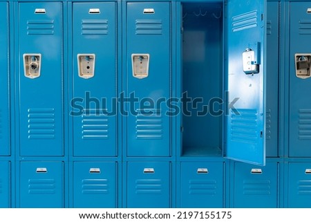 Single open empty blue metal locker along a nondescript hallway in a typical US High School.  No identifiable information included and nobody in the hall.  	 Royalty-Free Stock Photo #2197155175