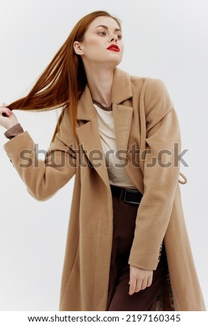 Professional redhead model posing on a white background in a coat. Advertising for brands showrooms catalog of clothing for women Royalty-Free Stock Photo #2197160345