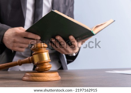 Lawyer hands holding a legal book and judge on table
