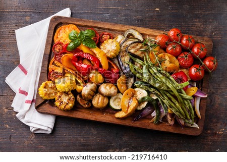 Grilled vegetables on cutting board on dark wooden background Royalty-Free Stock Photo #219716410
