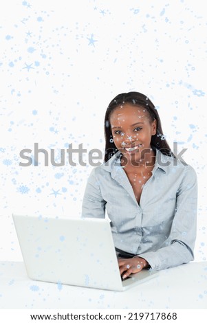Composite image of Portrait of a smiling businesswoman using a laptop with snow falling