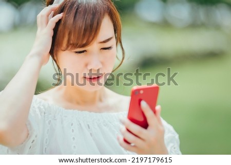 A woman using a smartphone (failure, stress) Royalty-Free Stock Photo #2197179615
