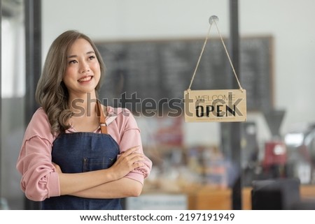 Shot of smiling Asian young sme small business owner wearing apron and standing white ipad and open sign coffee shop door, asian business woman barista cafe owner SME entrepreneur seller concept
