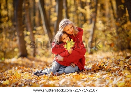 Mother and daughter sitting on a blanket in autumn forest