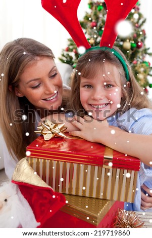Composite image of Smiling mother and her daughter holding Christmas gifts with snow falling