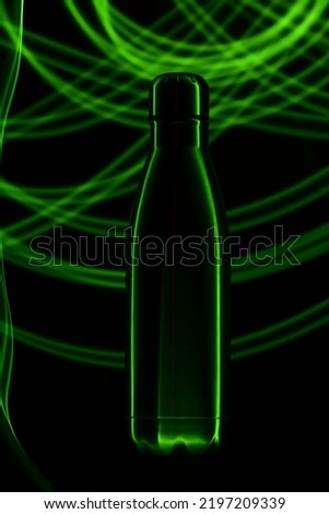 A Stainless-steel water bottle photographed using green light source with light painting concept.