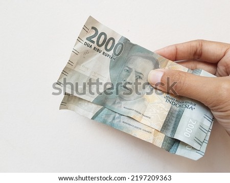 Mans hands holding money of Indonesia on white isolated background 

