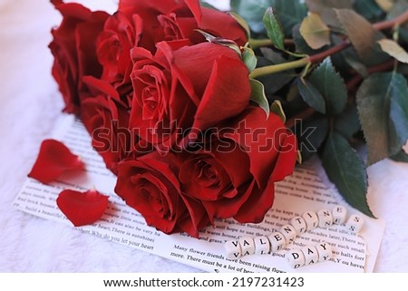 a bouquet of red roses and an inscription from the letters valentines day on a vintage newspaper on a plaid. The concept of romance, the morning of the holiday valentines day. 