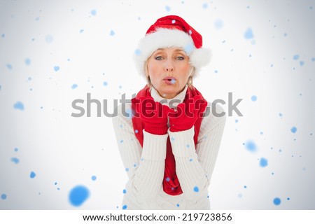 Composite image of festive woman blowing a kiss against snow falling
