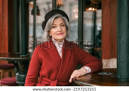 Elderly senior woman walking at cafe table in restaurant. Old retired aged lady on walk on city street. Stylish elegant elder person pensioner. Quite calm happy years in metropolis. Royalty-Free Stock Photo #2197253255