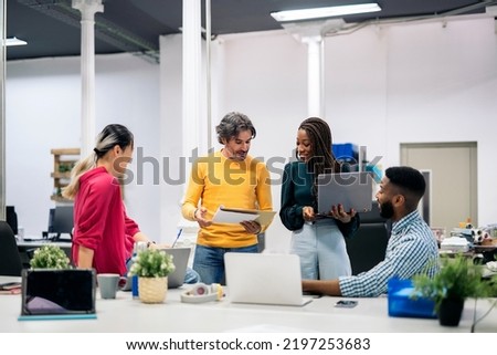 Multicultural teamwork talking and using laptops in a modern bright office. Co-working concept Royalty-Free Stock Photo #2197253683