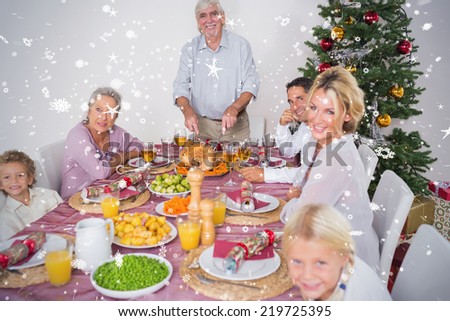 Composite image of Happy family at christmas dinner against snow falling