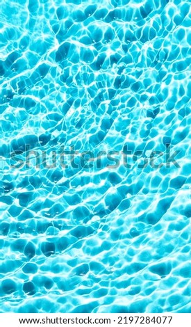 Beautiful tropical template with blue water texture background, water surface with sun rays reflection. Vertical photography.