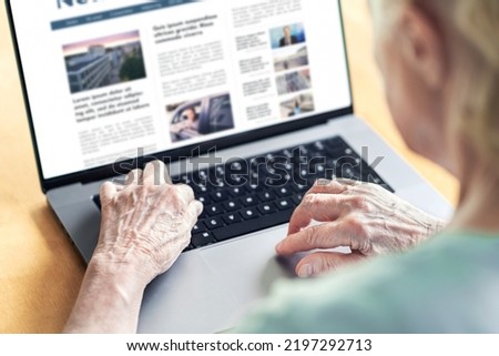 News website in laptop of an old woman. Elder senior and grandma reading digital newspaper with computer. Online magazine or web article in screen. Daily information publication site by the press. Royalty-Free Stock Photo #2197292713