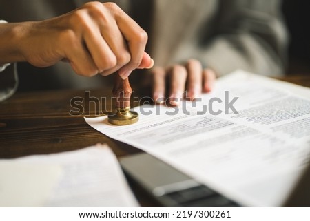 Close-up of person stamping documents to approve agreements, Royalty-Free Stock Photo #2197300261