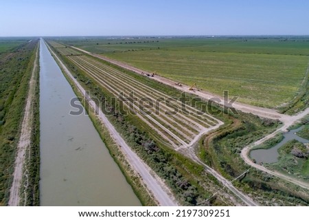 Artificial irrigation of the soil. Irrigation canal supplies water to irrigated land masses. Aerial View Royalty-Free Stock Photo #2197309251