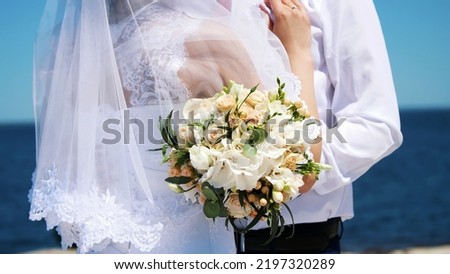 close-up of a wedding bouquet, amid hugs of newlyweds in wedding dresses. in the background sea and sky. High quality photo