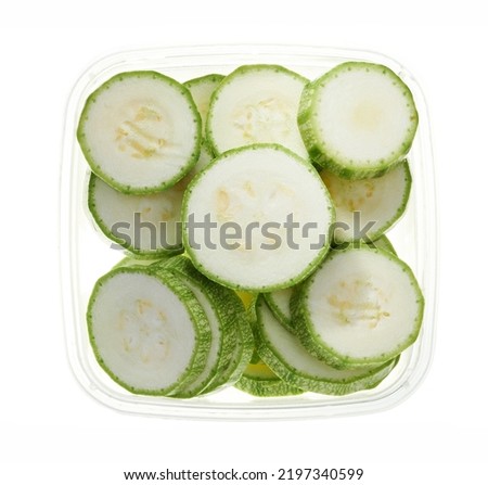 Slices of zucchiniin plastic container. Top view of raw vegetables isolated on white background. Preparing vegetables for freezing. Storage for winter storage in trays