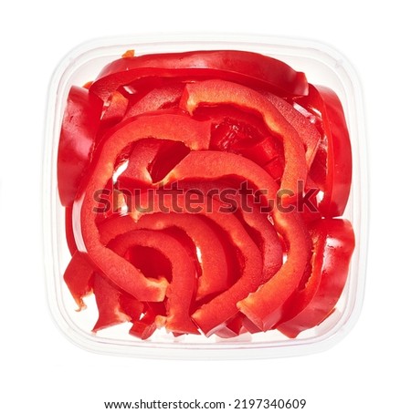 Slices of bell peppers in plastic container. Top view of raw vegetables isolated on white background. Preparing vegetables for freezing. Storage for winter storage in trays