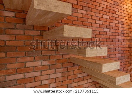 Wooden interior stairs that are attached only on the side on one side in a brick wall with a large load-bearing capacity. Royalty-Free Stock Photo #2197361115