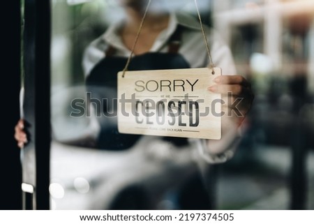 Store owner turning close sign broad through the door glass. small business owner concept.
