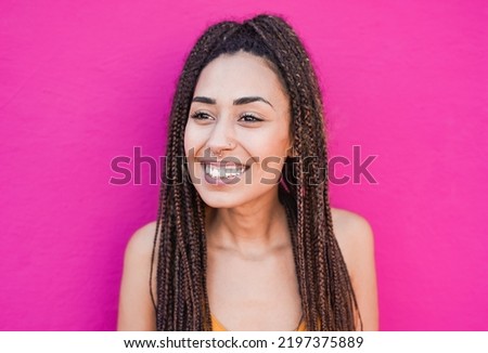 Happy young african girl smiling outdoor with pink wall in the background
