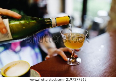 the bartender behind the bar pours wine