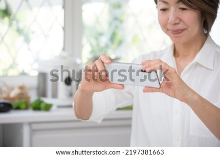 Middle-aged woman taking a picture with a smartphone