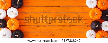 Halloween double border of black, white and orange pumpkins.  Top down view on an orange wood banner background. Copy space.