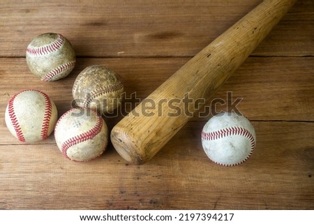 Close up old baseball and wooden baseball bat on a woodeb table. select focus.