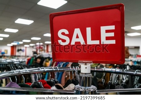 Red sale sign on rail of clothes in a high street shop or store