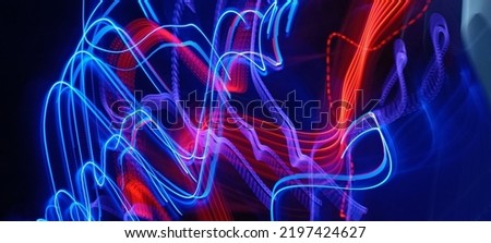 Blue and red light painting photography, long exposure fairy blue and red lights curves and waves against a black background. Long exposure light painting photography. Abstract pink purple swirls
