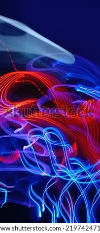 Blue and red light painting photography, long exposure fairy blue and red lights curves and waves against a black background. Long exposure light painting photography. Abstract pink purple swirls
