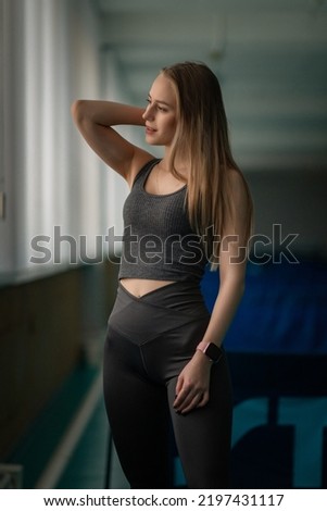 Young beautiful fair-haired girl in a sports uniform in the gym. There is artistic noise.