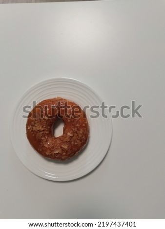caramel donut with white filling covered with icing in a plate, top view. Photo in light colors. one donut isolated on white plate space for text