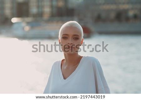 Portrait of young smiling millenial european short haired woman. Beautiful happy blonde girl outdoor. Summer fashion female clothing.