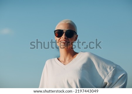 Portrait of young smiling millenial european short haired woman in sunglasses. Beautiful happy blonde girl outdoor. Summer fashion female clothing.