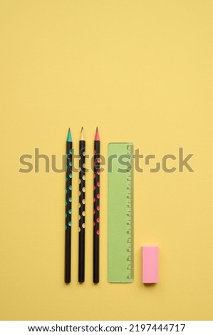 School supplies pencils, ruler and rubber isolated on yellow background, flatlay, minimal simple flat lay. Stationary stuff products for education, geometry tools. Back to school concept. Vertical