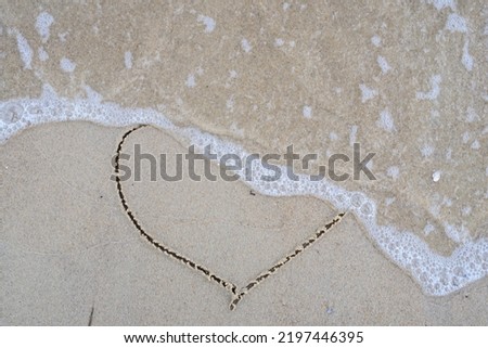 End of summer love, The concept of separation and loneliness. Selective focus. The sea wave washes picture of heart drawing on the sand. Ephemeral romantic love. Not true love. End of relationship.
