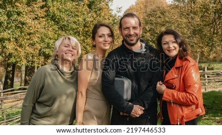 Group of happy people spending their weekend in nature. Portrait of joyful friends having good time relaxing together in summer park. Friends hugging and smiling at camera.