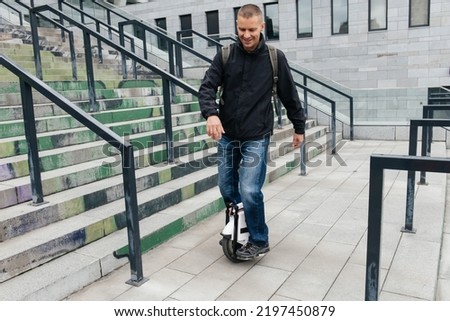Man riding fast on electric unicycle on city street. Mobile portable individual transportation vehicle. man on electric mono-wheel riding fast (EUC) to work Royalty-Free Stock Photo #2197450879