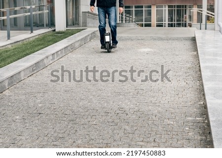 Man riding fast on electric unicycle on city street. Mobile portable individual transportation vehicle. man on electric mono-wheel riding fast (EUC) to work Royalty-Free Stock Photo #2197450883