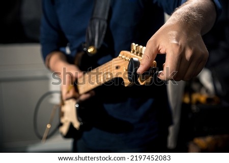 guitarist tuning electric guitar close-up Royalty-Free Stock Photo #2197452083