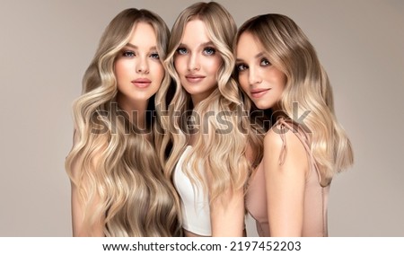Three beautiful women with hair coloring in ultra blond. Stylish hairstyle curls done in a beauty salon. Fashion girls , cosmetics and makeup. Royalty-Free Stock Photo #2197452203