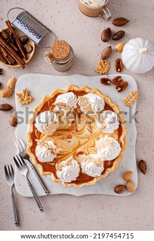 Pumpkin cheesecake swirl pie topped with whipped cream on a marble board, original Thanksgiving dessert idea