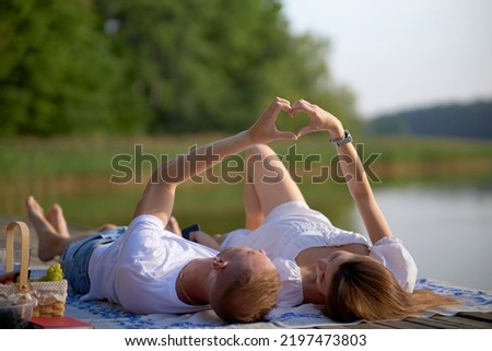 Valentine Couple. Portrait of Smiling Beauty Girl and her Handsome Boyfriend making shape of Heart by their Hands. Happy Joyful Family. Heart Sign. Valentines Day
