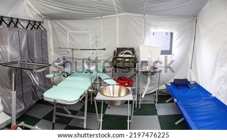 Tent operating room. Equipment for medical operating inside tent. Medical couches inside tent hospital. Location for operations. Rapidly erected hospital. Operating room of prefabricated room Royalty-Free Stock Photo #2197476225
