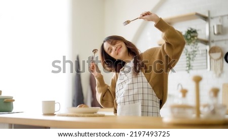 Asian young woman dancing in kitchen room. She happy and relaxing at free time on weekend Royalty-Free Stock Photo #2197493725