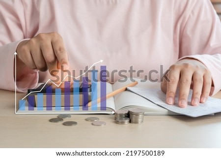 Woman do home accounting and calculating book bank statement for household expense with coins and business bar graph. Home accounting plan for monthly payment. Saving and accounting concept at home. Royalty-Free Stock Photo #2197500189