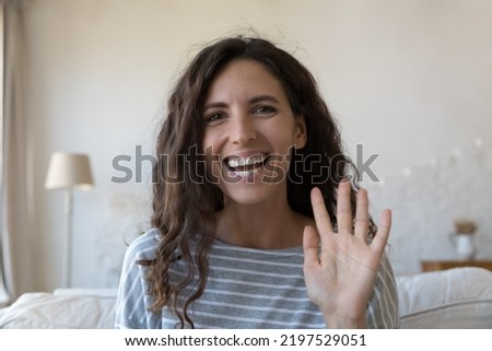 Beautiful Hispanic woman look at camera start video call, wave hand greets friend or family living abroad enjoy virtual meeting, remote talk using modern tech, head shot. Video conference app concept Royalty-Free Stock Photo #2197529051